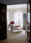 Blick durch offene Tür in traditionelles Wohnzimmer auf weisses Sofa und Fenster