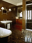 A traditional, period style brown bathroom, a free standing roll top bath, wash basin on stand, modern shower cubicle