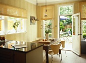 Retro style chairs and wooden table in dining area of open plan kitchen with view to garden