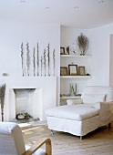 White sitting room with day-bed beside fireplace, armchair and wooden floor.