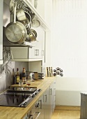 Modern kitchen with white walls, stainless steel cooker and splash back, ceramic hob, grey units, wooden work tops,