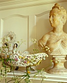 A decorative bowl next to a stone bust against a wood panelled wall