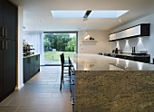 A stone dining table in an open-plan kitchen with terrace windows