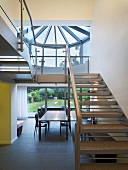 An open stairway with steel steps and a view of a dining table in front of a terrace window