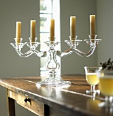 A five arm glass candle stick on a wooden table