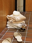 Woman's slippers, perfume, a bracelet and towels on a tiled floor