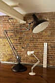 Two adjustable lamps and a thermometer against a stone wall