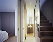 A view from a stairwell through an open door in to a bedroom and a bathroom