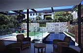 Retro-style armchairs in a living room in a newly built house with a view through a glass facade to an outdoor pool