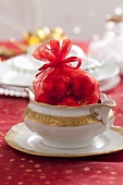 A red sack filled with Christmas baubles in a white sugar bowl