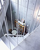 An open stairway with a view of a shelf in front of a concrete wall