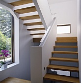 A modern white staircase with wooden stairs