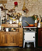 Ein altmodischer Ofen in einer Landhausküche mit hölzernen Schränken und Steinmauern