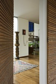Offene Haustür mit Holzverkkleidung und Blick in modernen Vorraum mit Kunstobjekt