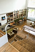 A view of a staircase in a modern living room with upholstered chairs and a parquet floor