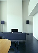 A view from a dining room into a living room with a sofa, a built-in fireplace and a floor lamp