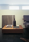 A walnut coffee table, books, a ceramic bottle and an acrylic painting by Ad