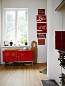 A simple red metal cupboard under a window