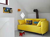 A yellow sofa in an attic room
