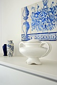 A soup tureen and vases on a shelf with an azulejo made of blue and white ceramic tiles above it