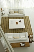 A view from a mezzanine floor of a living room with two white sofas and a coffee table