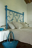 A blue wrought iron bed with white bedclothes