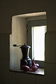 Eine alte Kaffeemühle und Zwiebeln in einer kleinen Fensternische