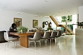 An elegant dining room with a large wooden dining table, modern, leather-covered chairs and antiques