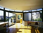 Open-plan room in contemporary penthouse with curved desk below window