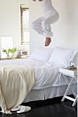Young woman jumping on a bed