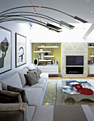 Modern sectional sofa and curved stainless steel lamp bodies in front of a fireplace and built-ins in niches