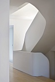 A view into a stairwell with curved steps and stone banisters