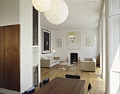 An elegant, modern open plan living room with a dining table and paper pendant lamps