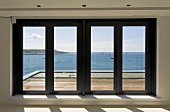 Glass patio doors in front of wood deck with a view of the ocean