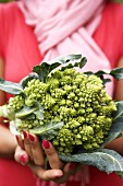 Woman holding a head of romanesco broccoli in her hands