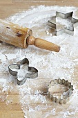 A rolling pin and cutters on a floured wooden board
