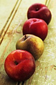 A row of plums on a wooden surface