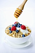 A bowl of muesli with fresh berries, yogurt and honey