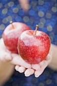 Frau hält zwei rote Äpfel