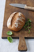 Bread on a chopping board with herbs and a knife