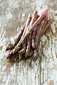 Purple asparagus on a wooden surface
