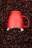 Eine Kaffeetasse zwischen Kaffeebohnen halb versenkt