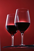 Two glasses of red wine against a red background