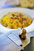 An alba truffle on grater with a truffle tajarin in the background