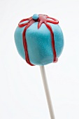 A blue parcel-shaped cake pop with a red iced bow
