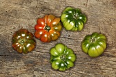 Red and green beefsteak tomatoes on a wooden surface