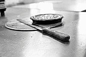 Knife and baking implements on a stainless steel cutting board in the kitchen