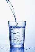 Mineralwasser wird in ein Wasserglas gegossen