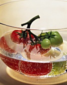 Red and green vine tomatoes in a dish of water