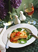 Poached salmon fillet with tomato sauce on leafy vegetables 